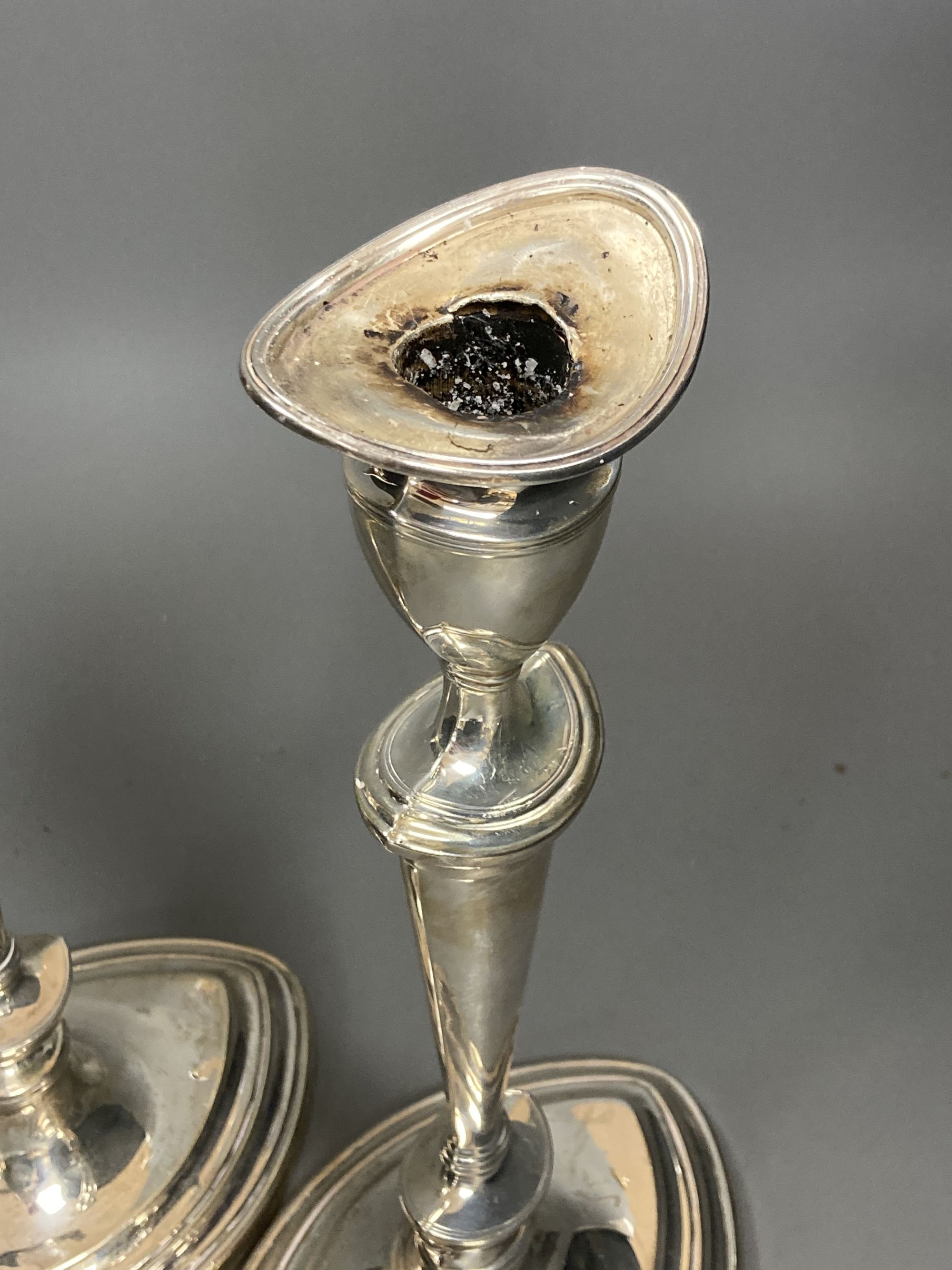 A pair of Edwardian silver oval candlesticks, by Goldsmiths & Silversmiths Co Ltd, London, 1903, loaded, 30.3cm, (sconces a.f. and stuck in situ).